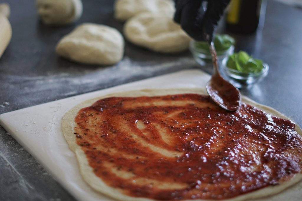 Eine Pizza auf einem Pizzastein und Tomatensoße